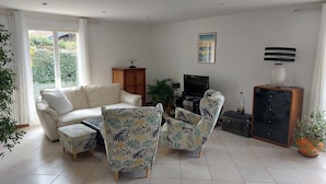 A living room with a sofa, armchairs, a TV, and a cabinet.