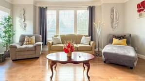 A living room with a sofa, armchairs, a coffee table, and a floor lamp.