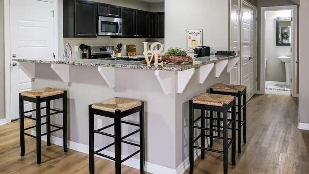 A kitchen with dark cabinets, a granite countertop, and three stools. - Spacious Home in South Tulsa- Finale Home. Close to major highways and Riverside (Tulsa)