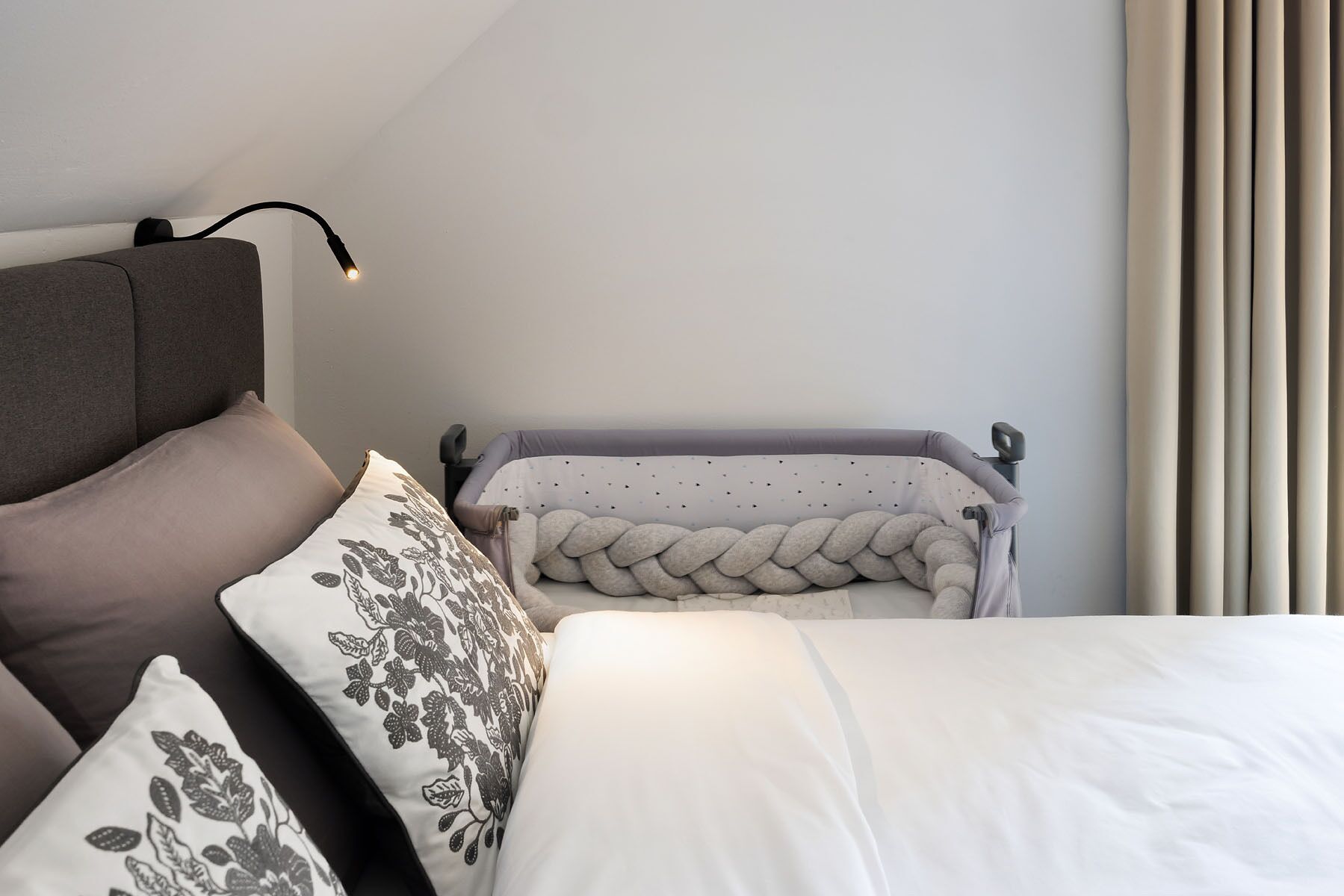 A bedroom with a bed, two pillows, a bedside table, and a lamp.