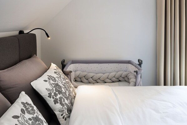 Quarto com cama, duas almofadas, mesa de cabeceira e abajur.