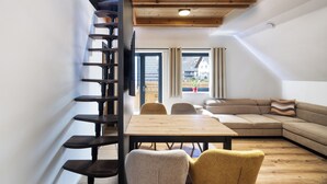 Un interior moderno con techo de madera, una mesa de comedor, un sofá y una escalera.