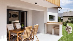 Un patio moderno al aire libre con una mesa y sillas de madera, un banco integrado pequeño y vistas del entorno.