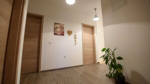 A hallway with wooden flooring, two doors, a wall-mounted light fixture, a potted plant, and a framed picture. - Vacation home near Split with private pool & garden (Kaštel Lukšić)