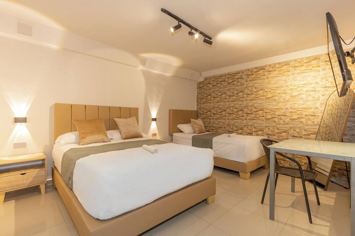 Ein modernes Hotelzimmer mit zwei Betten, einem Esstisch und einer Wand mit Steinverkleidung.