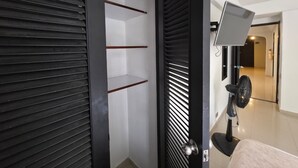 Una habitación moderna con puerta corredera, un ventilador de pie y vistas a otra habitación.