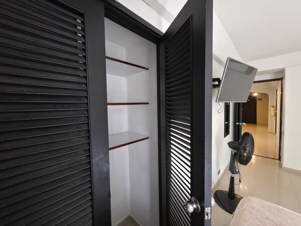 A modern room with a sliding door, a standing fan, and a view into another room. - Hotel Garden Laureles (Medellín)