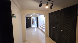 Un pasillo con suelo de baldosas, una escalera y una puerta con un letrero.