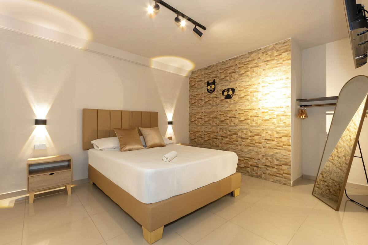 Ein modernes Schlafzimmer mit einem großen Bett, einem Nachttisch, einem wandmontierten Spiegel und einer strukturierten Wand.