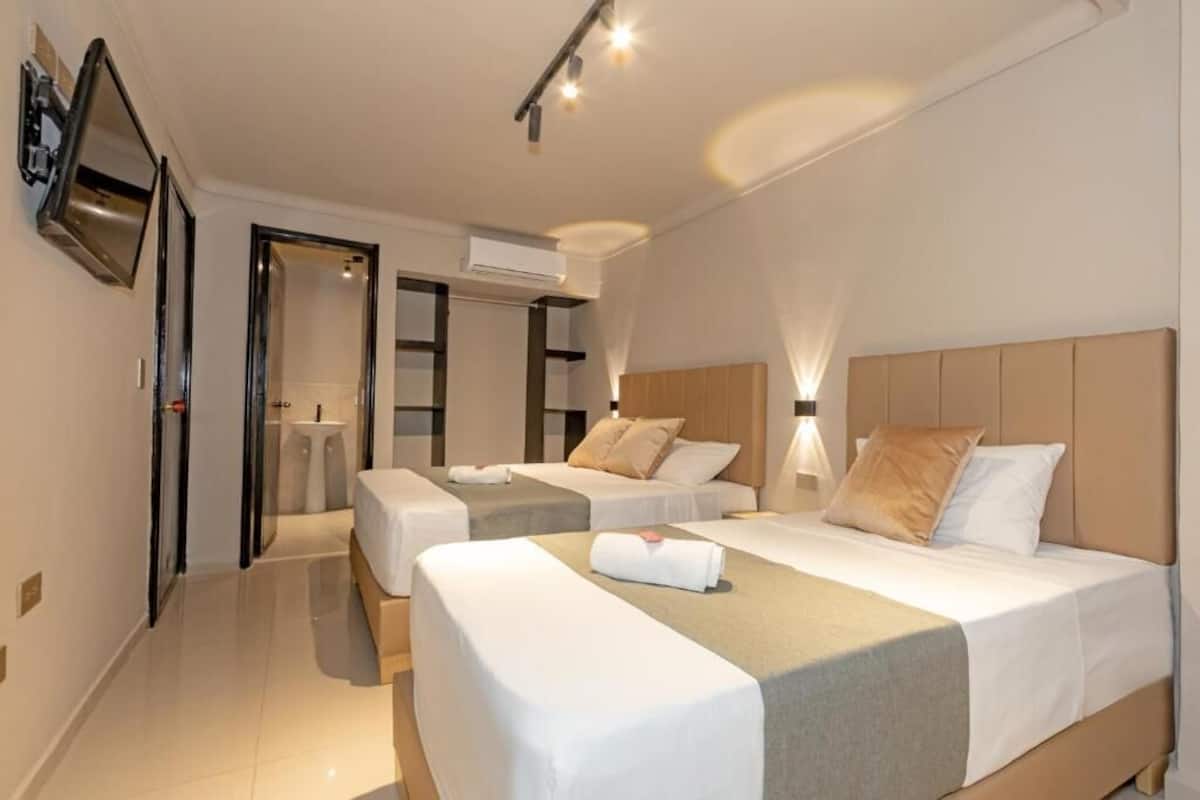 Ein Hotelzimmer mit zwei Betten, einem Fernseher, einer Klimaanlage und einem Spiegel.