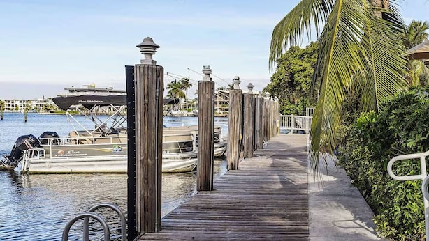 A wooden dock leading to a marina with boats, surrounded by lush greenery and palm trees. - 2bed/2bath Club Wyndham Santa Barbara resort. Across St frm Pompano Beach w/pool (Pompano Beach)