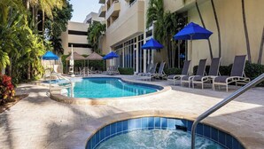A pool area with lounge chairs and umbrellas, surrounded by a building with balconies. - 2bed/2bath Club Wyndham Santa Barbara resort. Across St frm Pompano Beach w/pool (Pompano Beach)