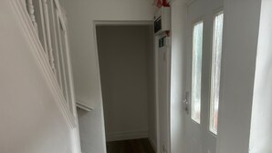 Un pasillo estrecho con suelo de madera, paredes blancas y una puerta con ventana.
