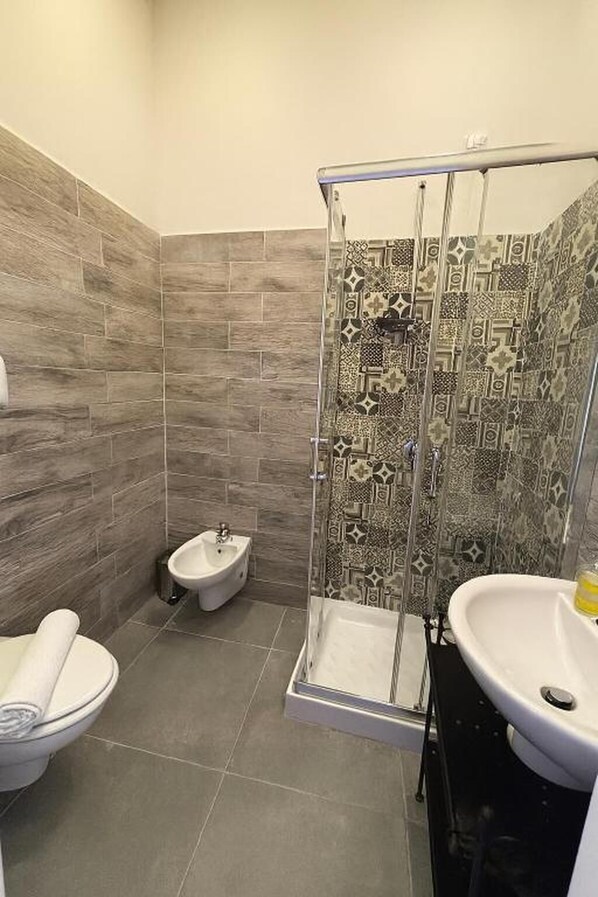 Une salle de bain équipée d’une douche, d’un bidet, de toilettes et d’un lavabo.