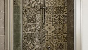 Ducha con puerta de vidrio y azulejos estampados.