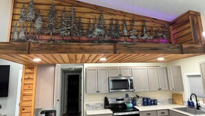 A kitchen with wooden ceiling beams, a microwave, stove, and cabinets.