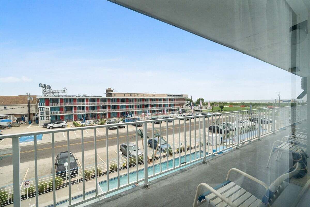 Vista desde un balcón sobre un estacionamiento con un edificio al fondo.