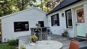A patio with a round table and two chairs, surrounded by potted plants and a small garden.