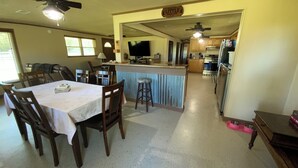 Comedor con una mesa lista para cuatro, cocina al fondo y un letrero que dice "Little House".