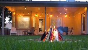 Un patio cubierto con una chimenea, muebles de exterior e iluminación colgante.