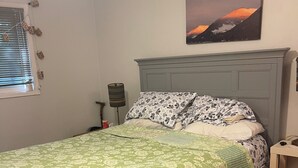 Une chambre à coucher avec un lit, une table de chevet, une lampe et un tableau au mur.