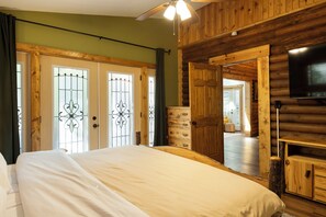 Une chambre de style chalet, avec un lit, une télévision et une porte en bois agrémentée d’un panneau de verre décoratif.