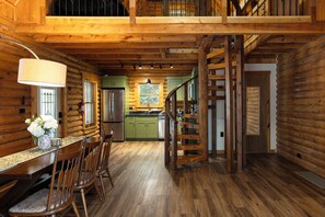 L’intérieur d’une cabane en rondins comprend un coin repas, une cuisine et un escalier.