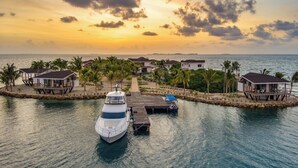 A waterfront property with a dock, a yacht, and several buildings with balconies. - Magenta Caye Luxury Private Island Resort - All inclusive (Placencia)