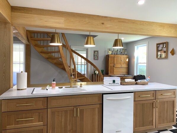 Una cocina con armarios de madera, encimera blanca y una escalera de madera.