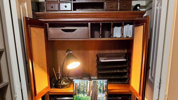 A compact home office setup with a wooden desk, a laptop, a desk lamp, and a chair.