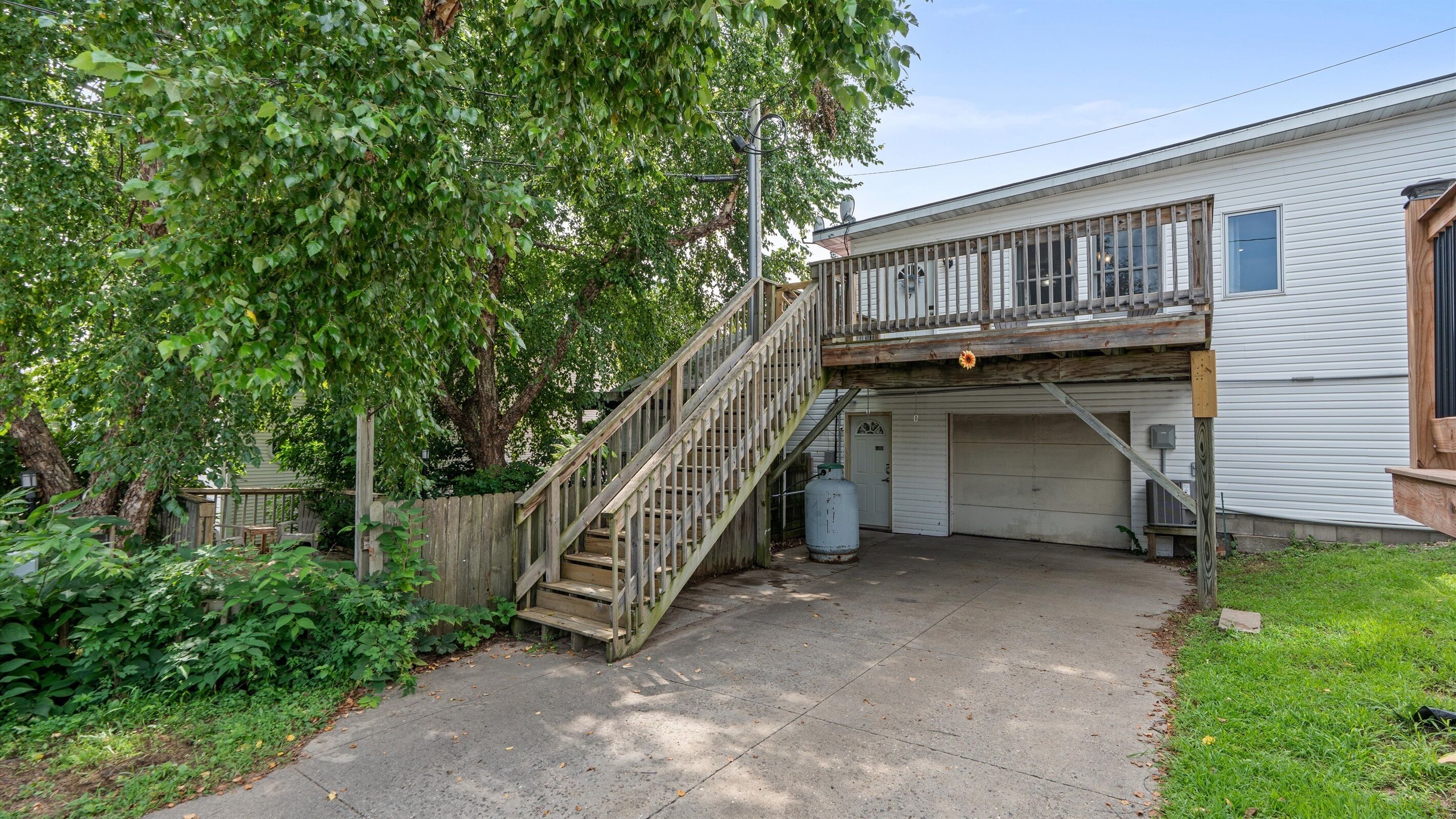 Ein zweigeschossiges Haus mit einer Holztreppe, die zu einer Garage führt.