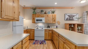 Una cocina con armarios de madera, microondas, estufa y refrigerador.