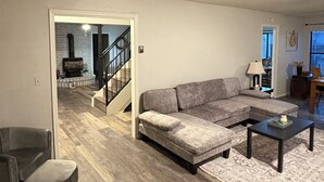 A living room with a sofa, coffee table, and a fireplace in the background. - Fabulous 4-bedroom pet-friendly house in Lakeside (Wagon Wheel)