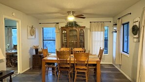 A spacious dining area with a wooden table and chairs, a ceiling fan, and a view of the kitchen through a window. - Fabulous 4-bedroom pet-friendly house in Lakeside (Wagon Wheel)