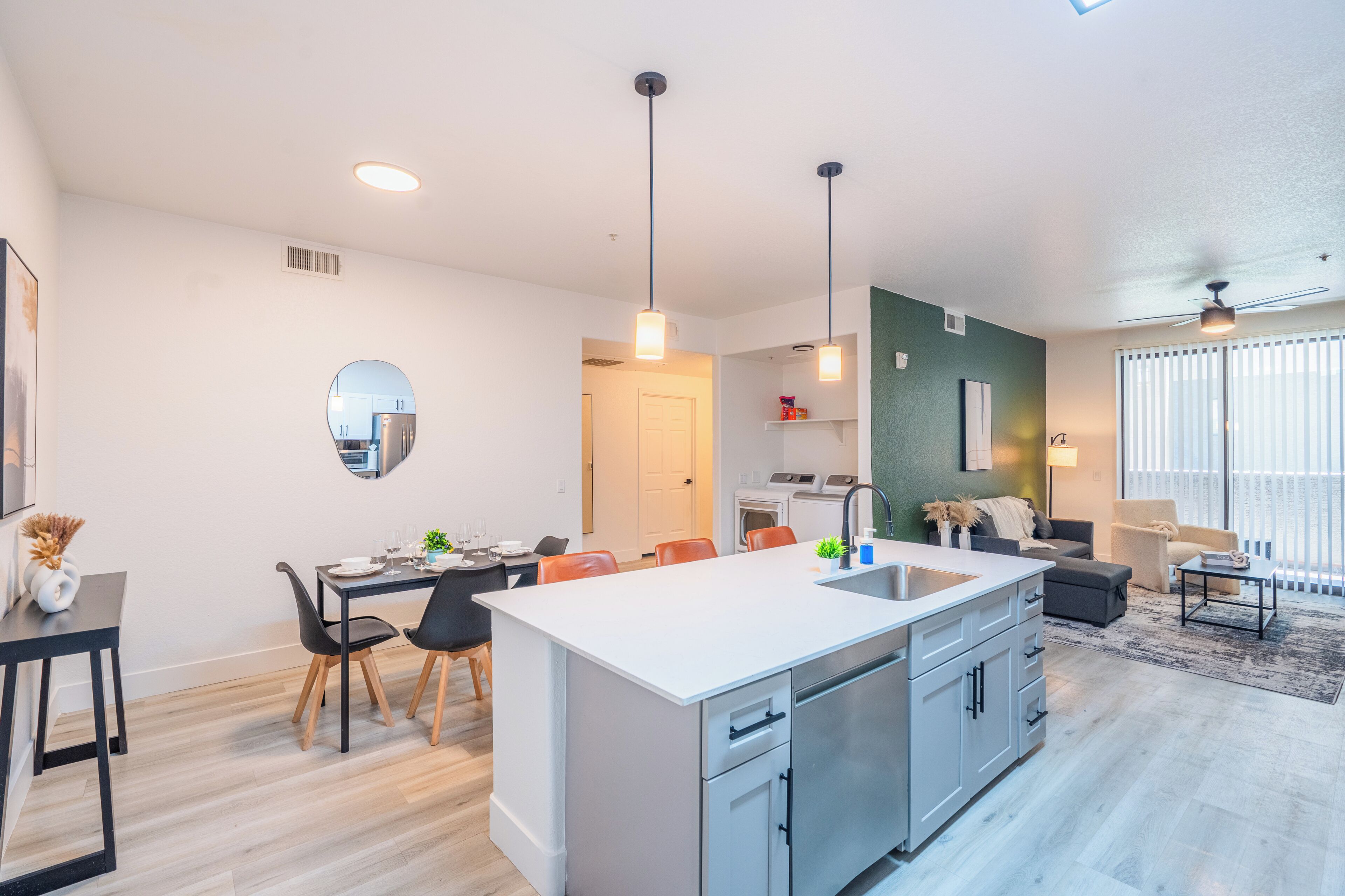 Una cocina moderna con una isla central, comedor con sillas y sala de estar con sofá y mesa de centro.