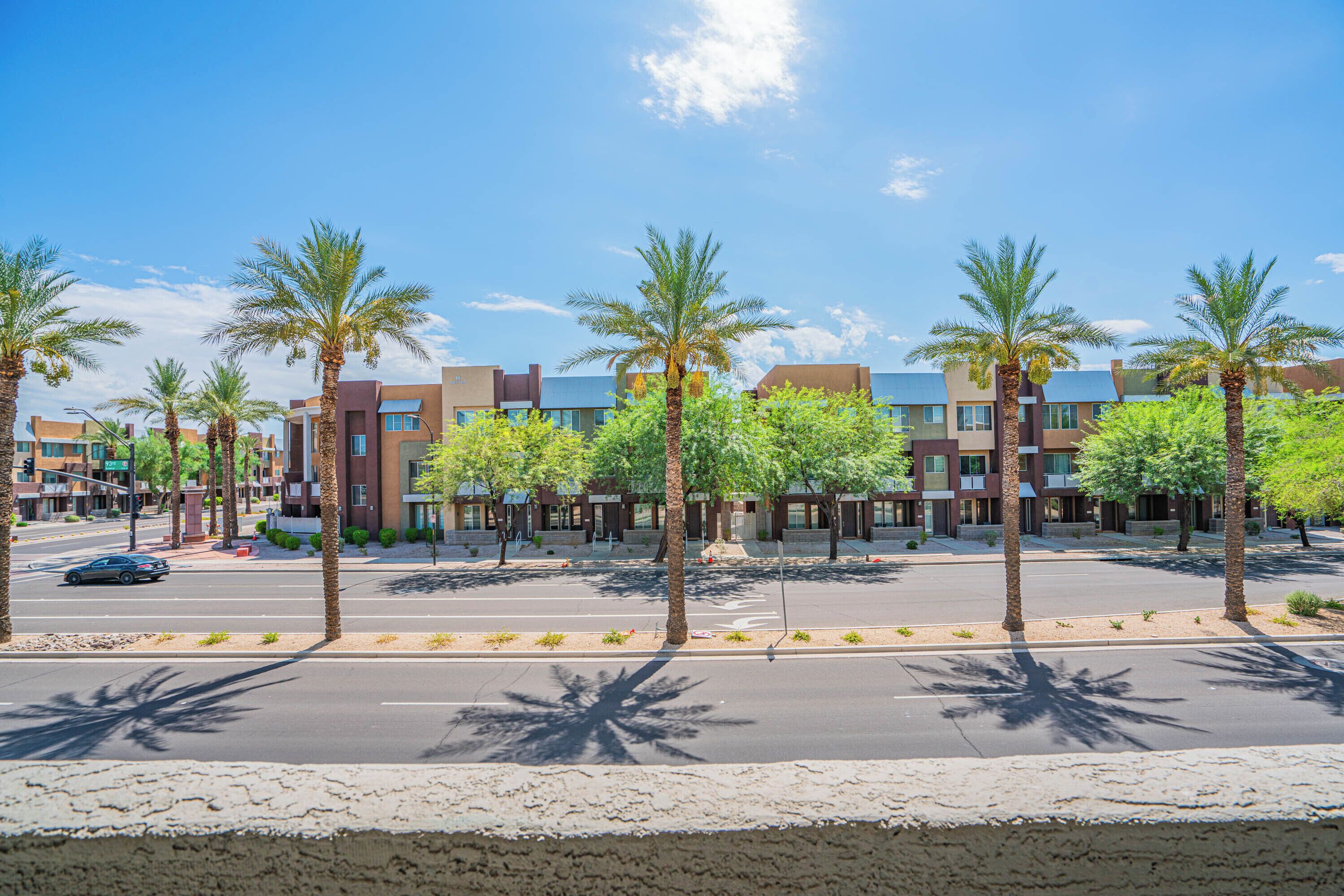 A street lined with palm trees and modern buildings.
