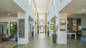 Un hall d’entrée spacieux avec un plafond haut, un escalier central et une table de billard.