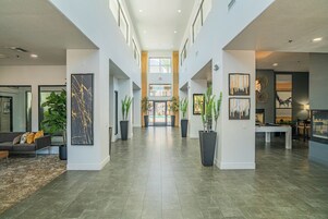A spacious lobby with a high ceiling, a central staircase, and a pool table.