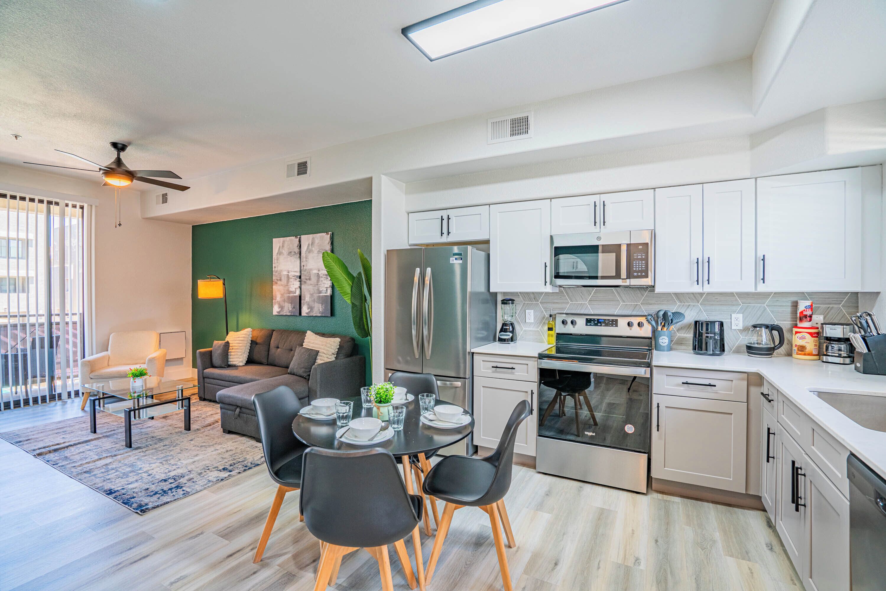 A modern kitchen with white cabinets, stainless steel appliances, and a dining area with a round table and chairs.