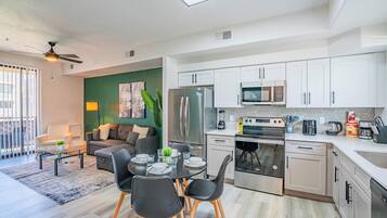 A modern kitchen with white cabinets, stainless steel appliances, and a dining area with a round table and chairs.