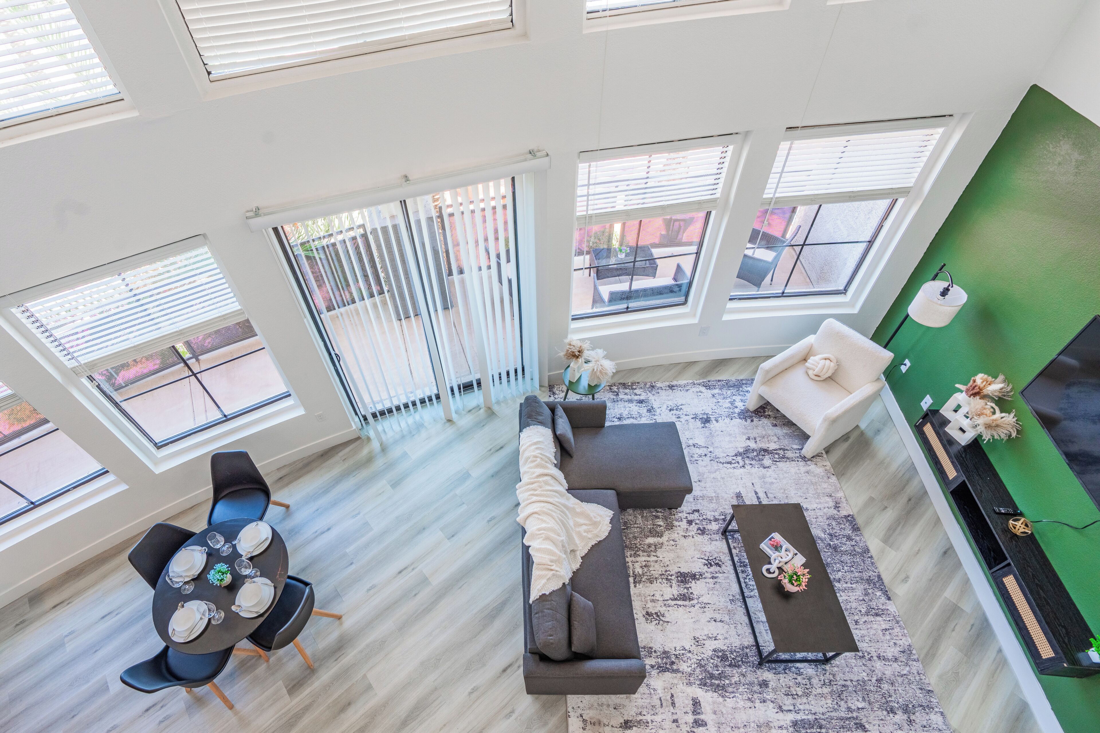 A modern living room with a sectional sofa, a dining table with chairs, and a green accent wall.