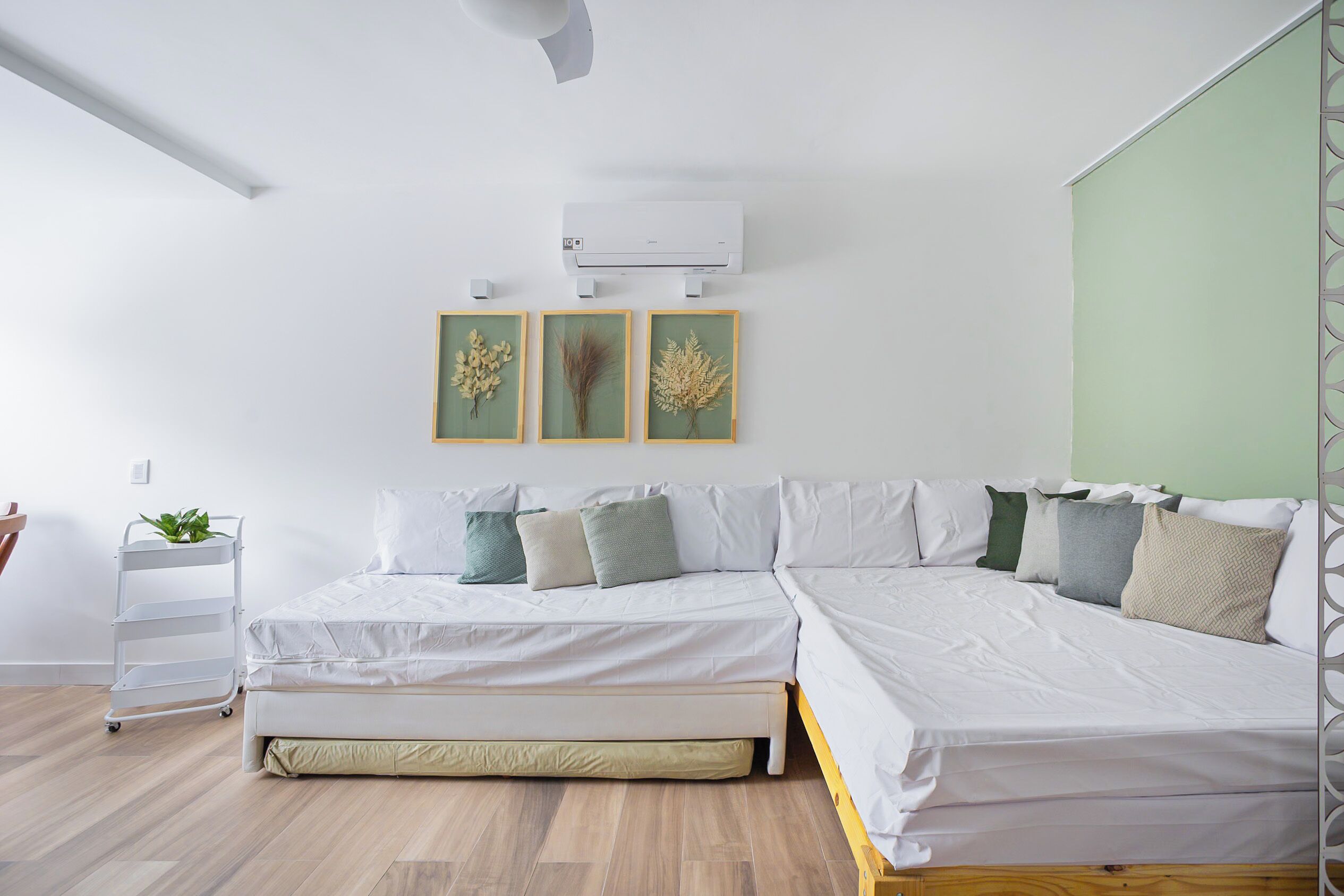 A modern bedroom with a bed, a small plant, and a wall-mounted air conditioner.