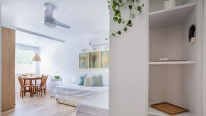 A modern bedroom with a bed, bedside tables, a desk, and a dining area. - FLAT NA AREIA DA PRAIA DE GARATUCAIA, ANGRA DOS REIS (Angra dos Reis)