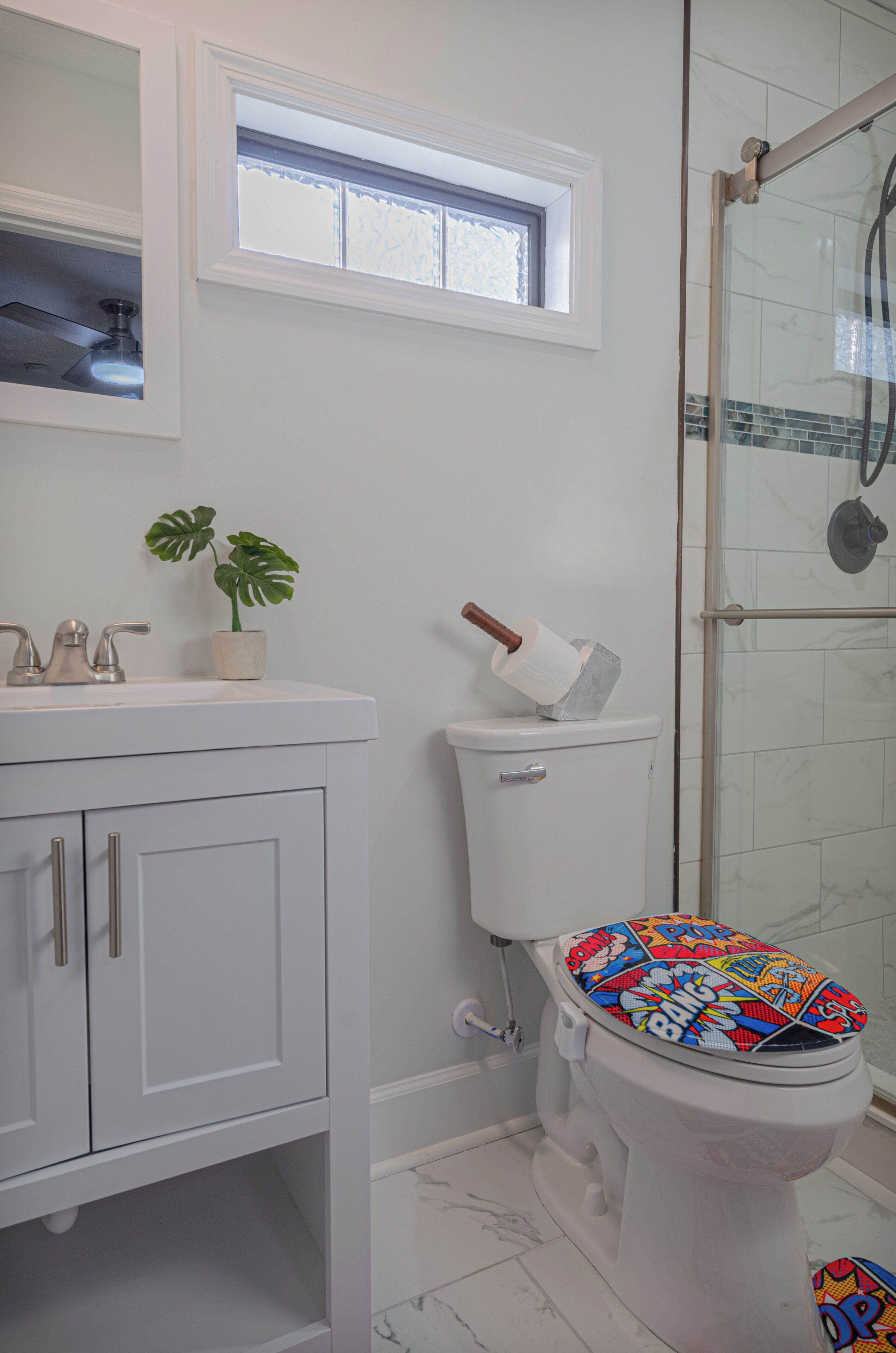 Une salle de bain comprenant des toilettes, un lavabo, un meuble de rangement et une fenêtre.