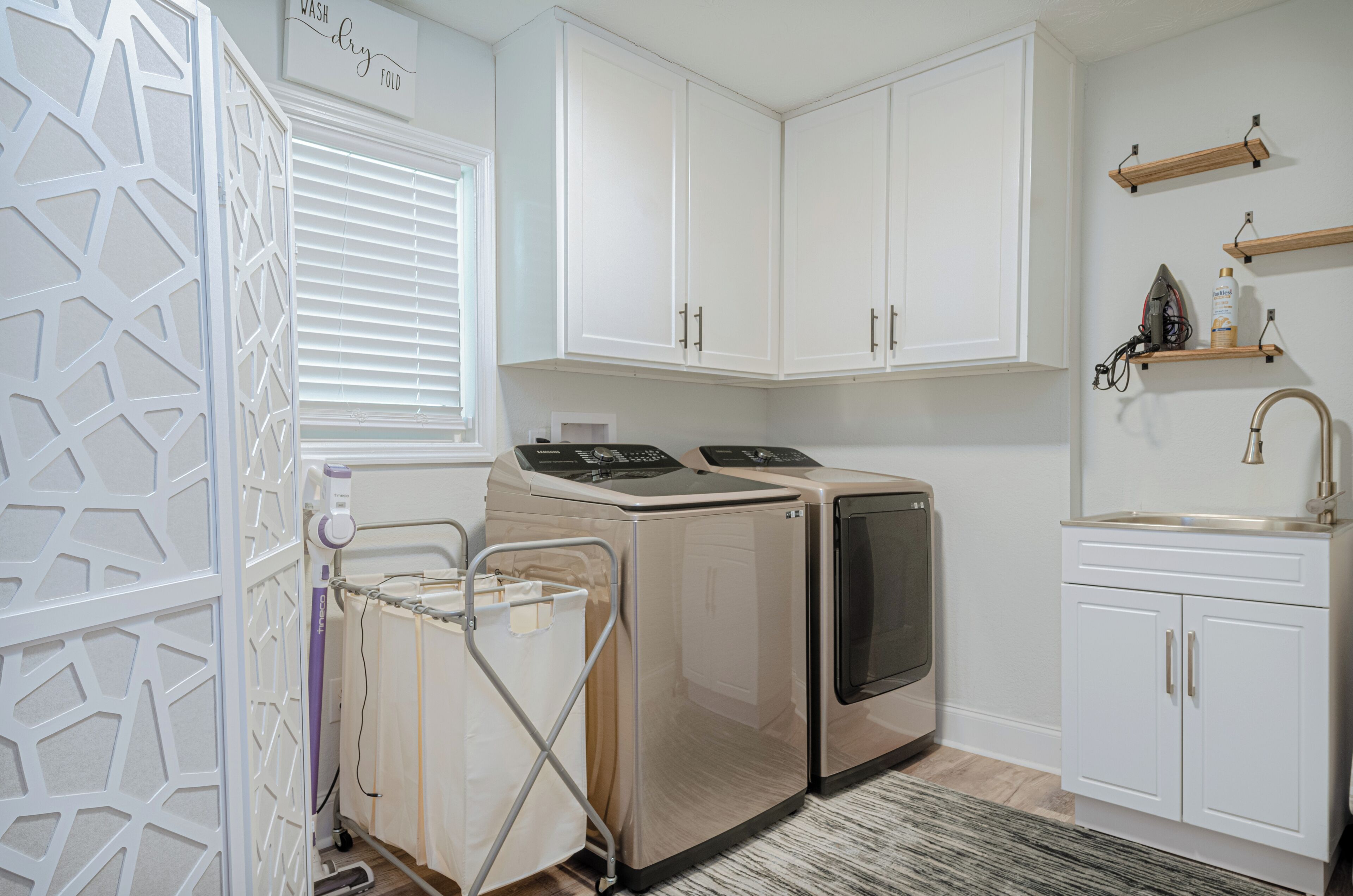 A laundry room with a washing machine, dryer, and ironing station.