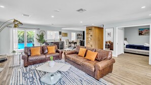 A spacious living area with leather sofas, a glass coffee table, and a view of a pool. - Spacious Palm Paradise Retreat -Heated Pool East Delray - Near The Beach- 4/3 (Delray Beach)