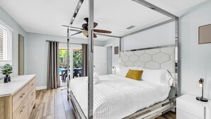 A modern bedroom with a four-poster bed, a ceiling fan, and a view of the outdoors. - Spacious Palm Paradise Retreat -Heated Pool East Delray - Near The Beach- 4/3 (Delray Beach)