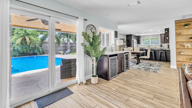 A modern living area with a pool view, a kitchen, and a dining area. - Spacious Palm Paradise Retreat -Heated Pool East Delray - Near The Beach- 4/3 (Delray Beach)