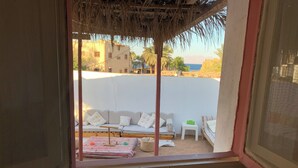 Habitación con ventana que da a un sofá blanco, una mesita y un tapete estampado.