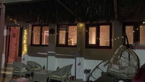 Un espacio al aire libre acogedor con mesa y sillas, una silla colgante y luces de cuerda.